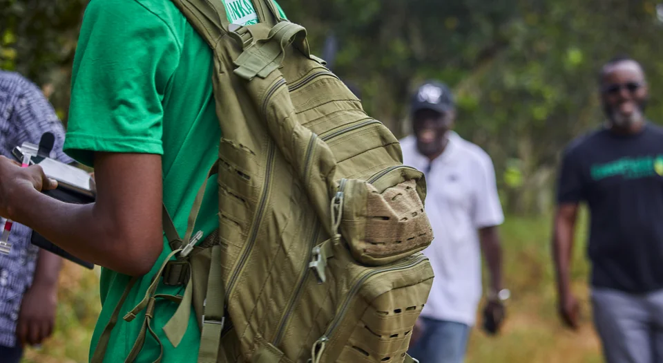 Visitors walk into the orchard, one with a backpack.