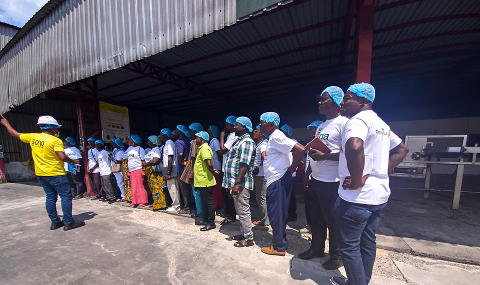 Visitors in hairnets gather outside a processing factory.