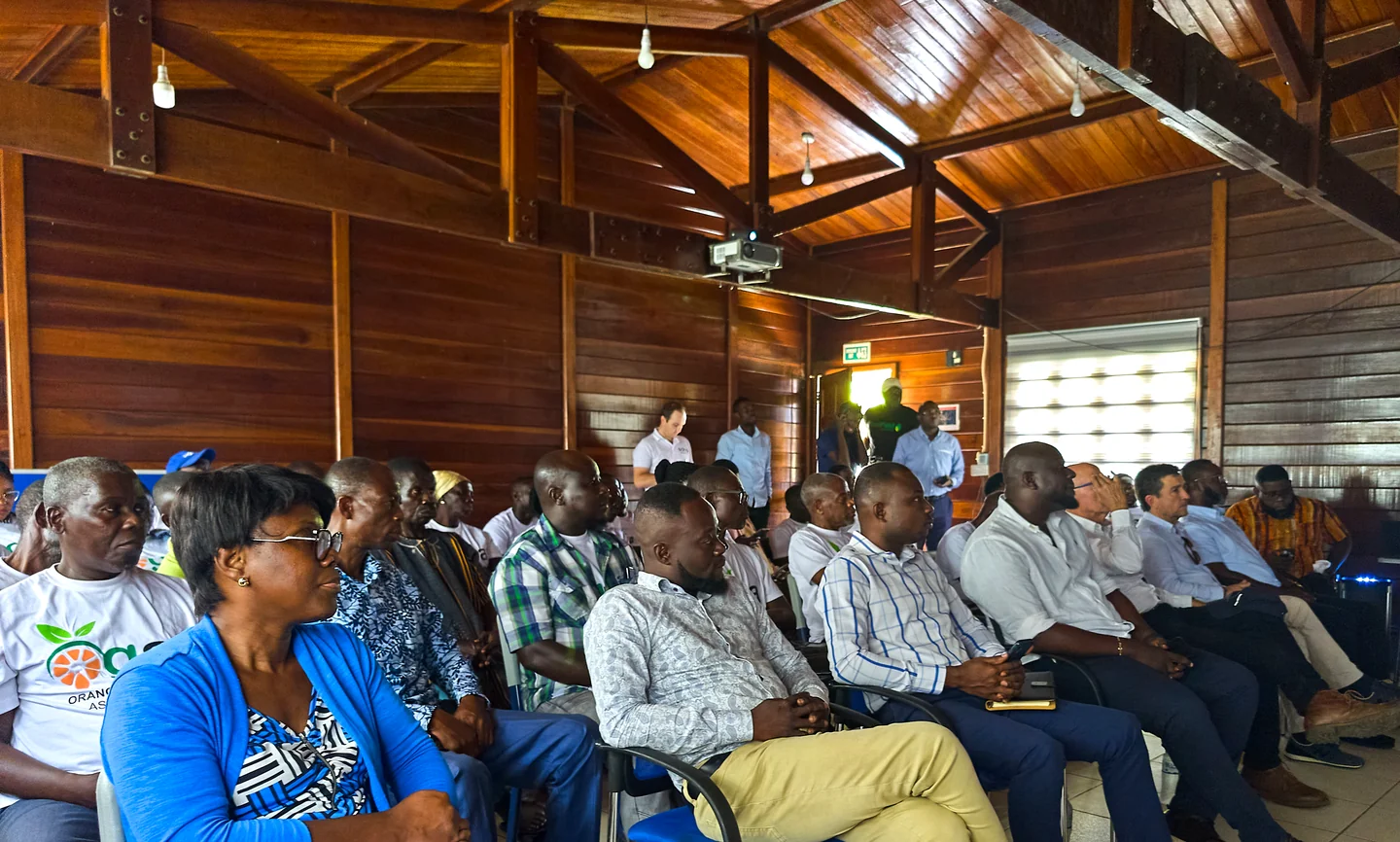 OGA members listen, seated in rows in a wooden hall.