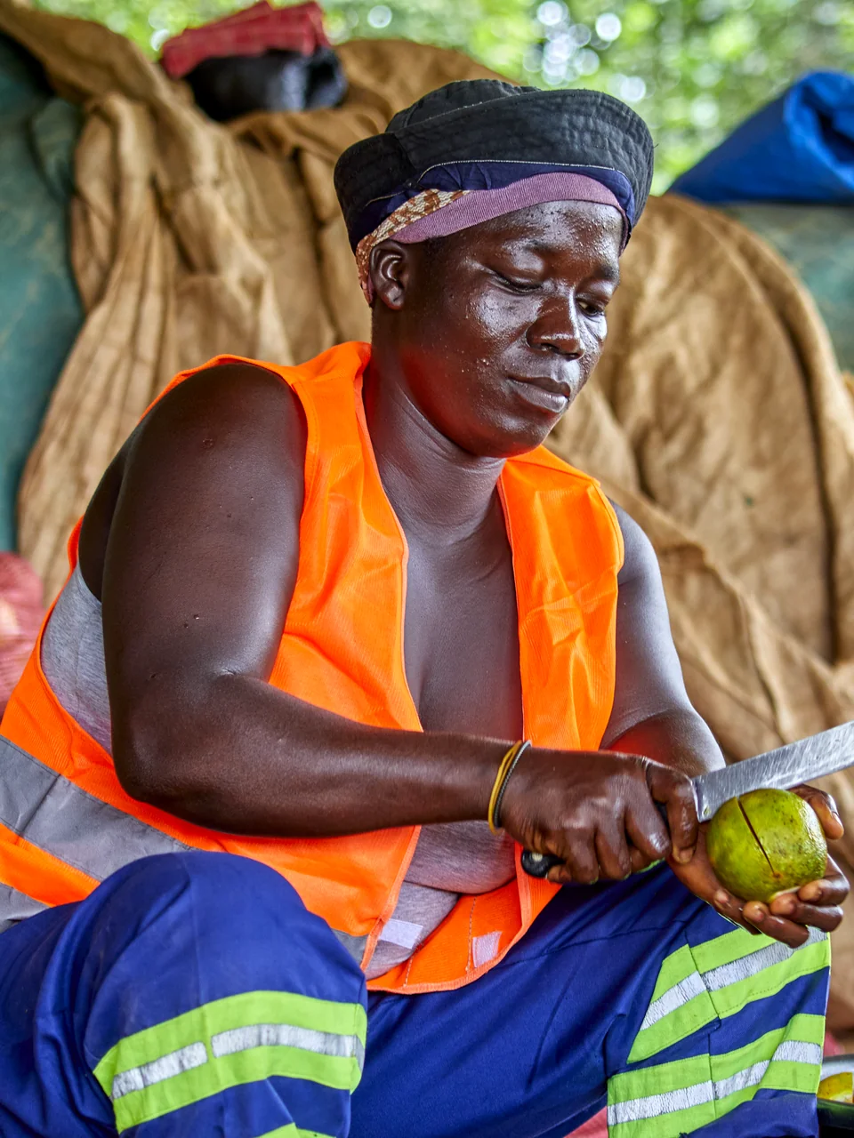 A packer in an orange safety vest cuts an orange.